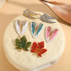 Elegante vleugel- en bladbroches met fonkelende kristallen op een beige voetstuk