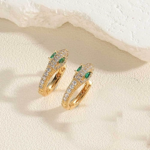 Détail de boucles d'oreilles serpent avec cristaux blancs et yeux verts sur pierre