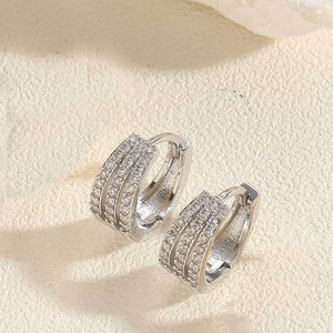 Gros plan de boucles d'oreilles huggie en argent avec trois rangées de zircons blancs