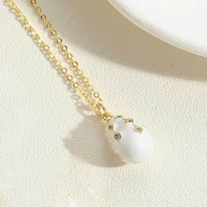 Macro detail of white enamel waterdrop pendant with gold stripes and zircon stones