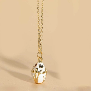 Detail of egg-shaped enamel pendant with golden leaf relief and O-chain design