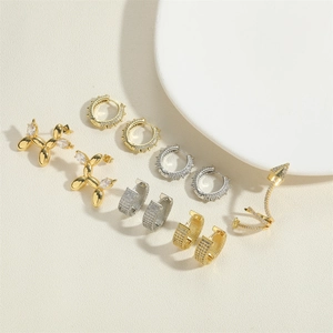 Detalle de aretes de aro con circón y espinas y pendientes de perro globo bañados en oro 14K