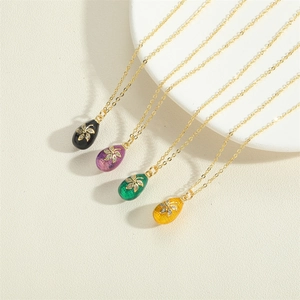 Detailed view of four colorful enamel egg pendants with zircon floral centers on gold chains