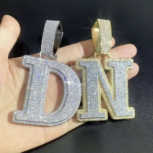 Makro-Detail von Iced-Out D und N Buchstaben-Anhängern mit silbernem und goldenem Finish