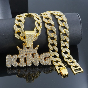Detail of hip hop iced out KING crown pendant with gold cuban link chain