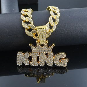 Macro shot of gold hip-hop KING pendant with crown and iced-out stones on a cuban chain