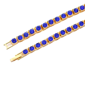Chaîne tennis dorée avec zircons bleus ronds et fermoir pliable sur fond blanc pur