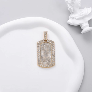Close-up of a gold hip hop square pendant with sparkling pavé-set crystals on a white tray