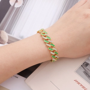 Close-up of gold Cuban chain bracelet with green enamel and pavé rhinestones on wrist