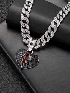Macro shot of iced-out Cuban link chain with a black broken heart pendant on leather