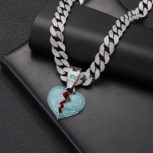 Macro detail of iced-out blue broken heart pendant on silver hip-hop Cuban link chain