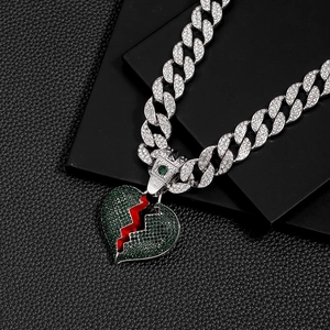Macro shot of silver Cuban chain with iced-out green broken heart pendant and red crack detail