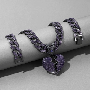 Macro detail of dark metal Cuban chain with purple crystal encrusted broken heart charm