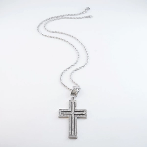 Macro shot of a silver iced-out cross pendant with zircon stones and a twist rope chain