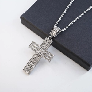 Macro shot of silver plated iced out cross pendant with sparkling crystals on rope chain