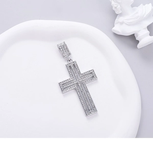 Luxurious silver iced-out cross pendant with sparkling zircons on a white ceramic tray