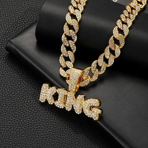Close-up of golden iced out KING pendant with white rhinestones on thick Cuban chain