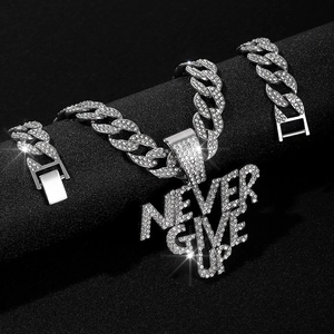Detailed close-up of NEVER GIVE UP pendant with iced-out crystals on Cuban link chain