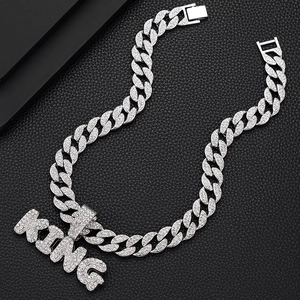Détail d'une chaîne cubaine argentée avec un grand pendentif lettre KING givré