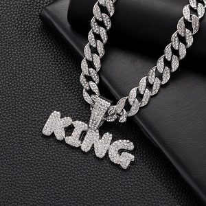 Macro shot of silver Cuban chain with KING letter pendant encrusted with white crystals