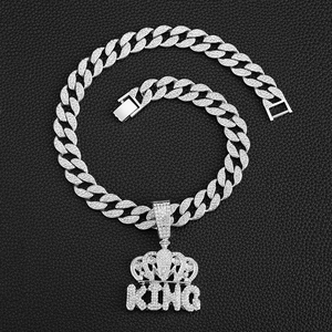 Macro view of iced-out silver KING crown pendant on thick Cuban link chain texture