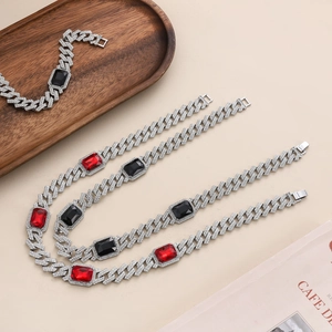 Macro detail of Cuban link necklace and bracelet set with red and black gemstones