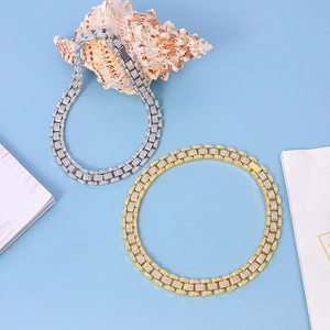 Detail of silver and gold Cuban link chains with iced-out rhinestones on blue background