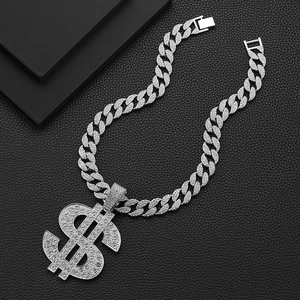 Silver Cuban link necklace with iced out dollar sign pendant on black leather background
