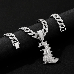 Macro detail of iced-out Cuban chain and silver dinosaur pendant with CZ stones