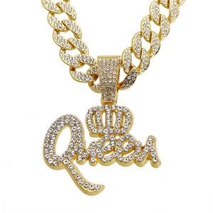 Dettaglio del ciondolo queen dorato con strass e corona su una catena a maglia