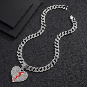 Détail d'une chaîne cubaine argentée avec pendentif cœur brisé serti de strass