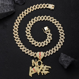 Détail macro du collier NO LOVE coeur brisé doré avec zircones et chaîne cubaine