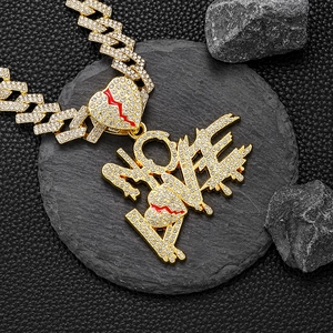 Détail macro du pendentif hip hop NO LOVE doré avec cœurs rouges brisés et strass
