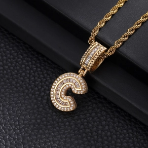 Macro detail of iced-out letter C pendant with sparkling zircons on gold twisted rope chain