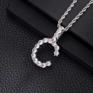 Macro shot of silver letter G pendant with cubic zirconia on a thick rope chain