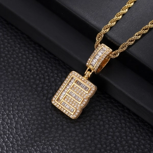 Detailed macro view of iced out letter E pendant with zircon stones on gold rope chain