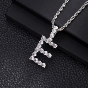 Close-up of iced out initial E pendant with cubic zirconia stones on rope chain.