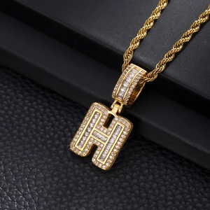 Macro detail of gold letter H pendant with iced out cubic zirconia and rope chain