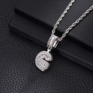 Macro d'un collier hip hop argenté avec pendentif lettre G et pierres zircone glacées