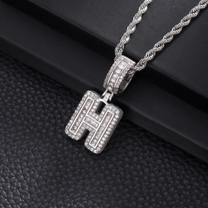 Détail macro du pendentif lettre H serti de zircons brillants avec sa chaîne torsadée