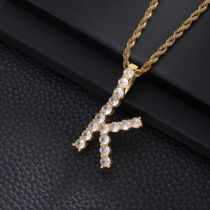 Macro shot of gold K-letter pendant with micro-paved zircons on a rope chain necklace