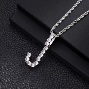Macro detail of silver-tone letter J pendant with cubic zirconia on a rope chain