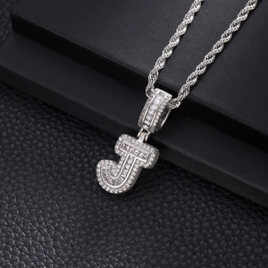 Détail d'un pendentif lettre J argenté serti de zircons avec une chaîne de style torsadée