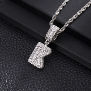 Vue macro du pendentif lettre K hip-hop argenté avec oxydes de zirconium sur cuir