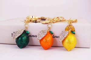 Detail of three lemon fruit keychains with sparkling rhinestones and gold plating