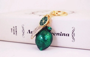Close-up of green enamel lemon keychain with crystal leaf and golden ring hook
