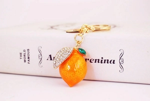 Macro detail of lemon keychain with orange enamel and sparkling white rhinestones