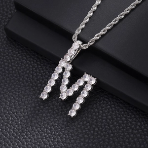 Detailed close-up of iced out letter M pendant with double-row cubic zirconia on rope chain