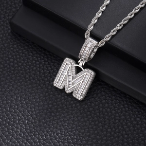 Gros plan du pendentif lettre M argenté avec zircons baguette et ronds incrustés