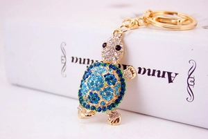 Close-up of sparkling blue rhinestone turtle keychain with a golden alloy base